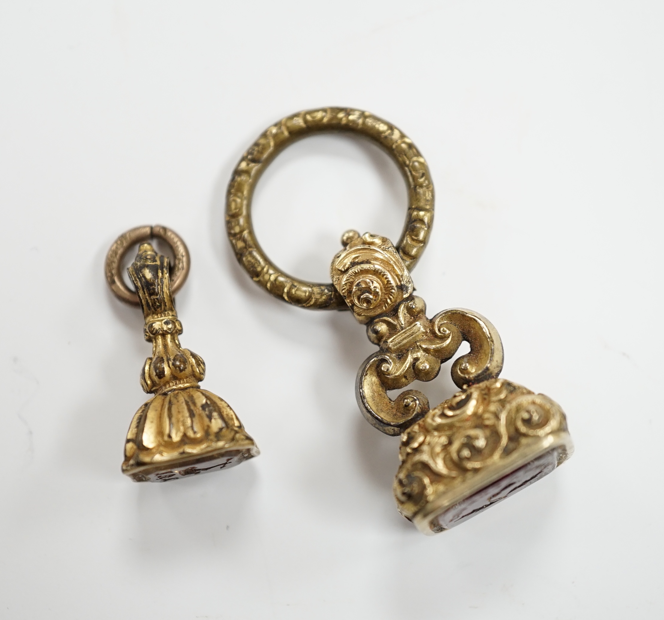 Two 19th century yellow metal overlaid and gem set fob seals, the largest with matrix carved with thistle and motto, 25mm.